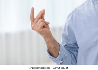 Man snapping his fingers indoors, closeup. Bad habit