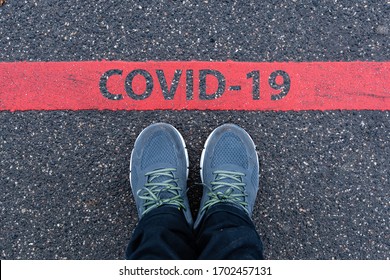 Man In Sneakers Standing Next To A Red Line With Text COVID-19, Restriction Or Safety Warning Concept