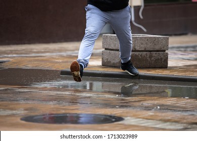 man in sneakers and sweatpants jumps over a puddle. - Powered by Shutterstock