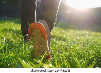 A Man In Sneakers Walks On Green Grass. Sport. Spring. Low Angle Back Shot.