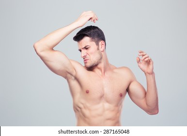 Man Sniffing His Armpit Over Gray Background