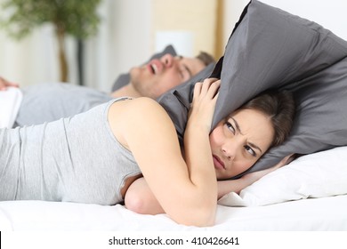 Man snoring while his wife is covering ears with the pillow - Powered by Shutterstock