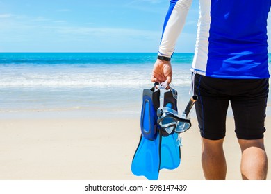 Man with snorkeling gear in hands going to sea on beach - Powered by Shutterstock