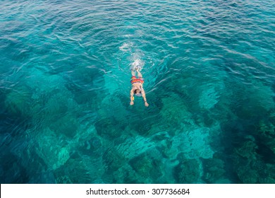 Man snorkeling over coral reef with clear blue ocean water, top view - Powered by Shutterstock