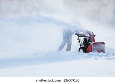 man with a snow blowing machine working in winter day