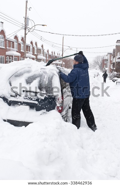 Man with a\
snow shovel. Car and street under\
snow.