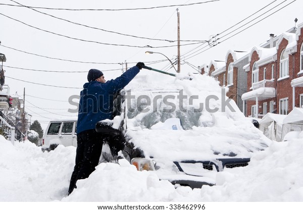 Man with a\
snow shovel. Car and street under\
snow.