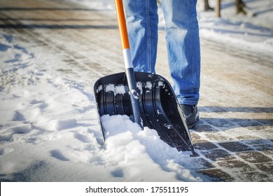 Man with snow shovel cleans sidewalks in winter