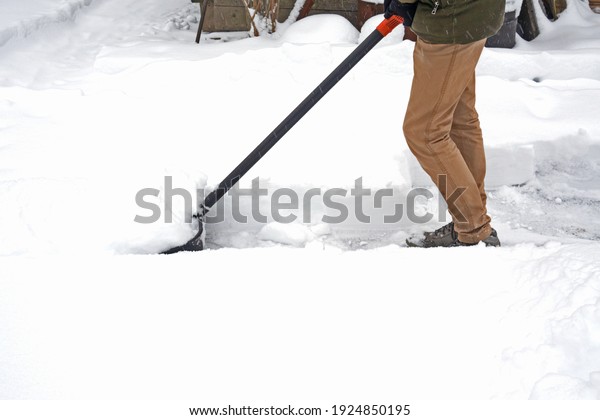 Man with snow shovel cleans sidewalks in winter.
side view