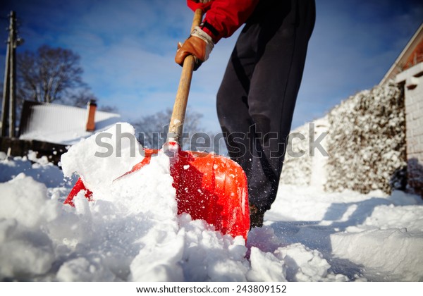 Man with snow shovel cleans sidewalks in winter.\
Winter time. Latvia. Europe.\
