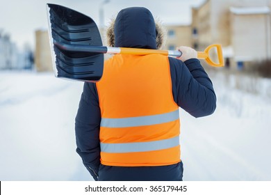 Man with snow shovel near building in winter 
