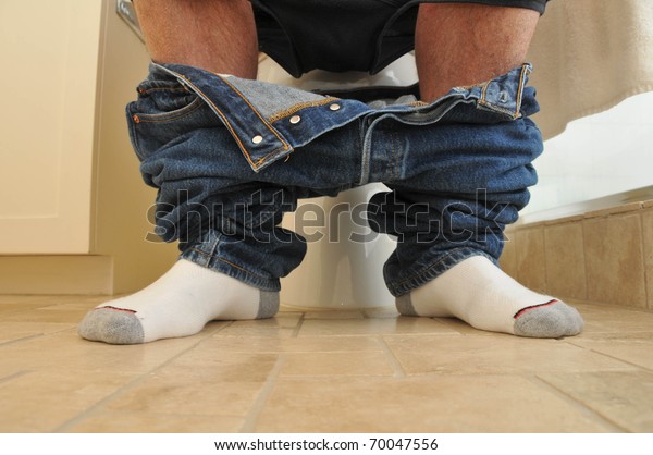Man with\
socks on and pants down on the\
toilet.