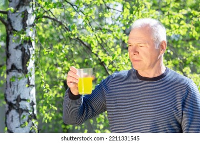 A Man With A Soluble Fizzy Vitamin Drink Against The Background Of Spring Foliage