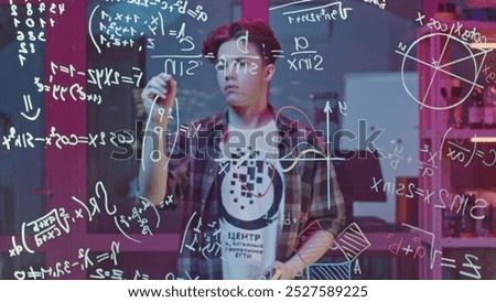 Man solves equations on transparent board. Media. Young man solves equations in closed laboratory. Man solves mathematical equations on blackboard with marker