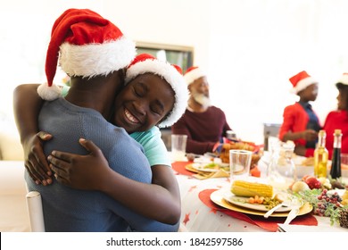 Man and son hugging each other while sitting and having lunch on dining table in the living room at home. christmas festivity tradition celebration concept