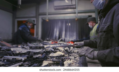 Man sorts garbage, electronics or plastic. Taking care of the environment. Waste recycling plant or garbage factory. Conveyor belt, trash moving along the line. Male have a eco-friendly work - Powered by Shutterstock