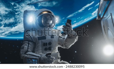 Man in a Space Suit Casually Talking on a Mobile Phone in Space While Servicing A Satellite. Astronaut Chatting with Mission Control Crew, Family or Colleagues on a Video Call on a Smartphone