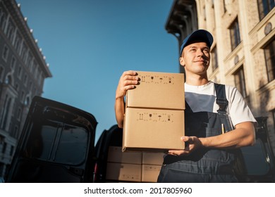 A man in a special comfortable uniform for an employee. Cardboard boxes with home delivery. Logistics courier express service for the delivery of goods from the online store.