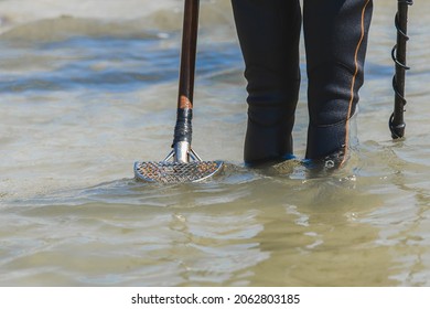 A Man With A Special Device And Equipment Metal Detector Looking For Lost Jewelry And Gold In Sea Water Near The Beach.