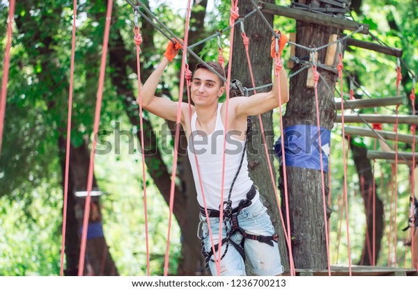 Man spend their leisure time in a ropes course. Man\
engaged in rope park.
