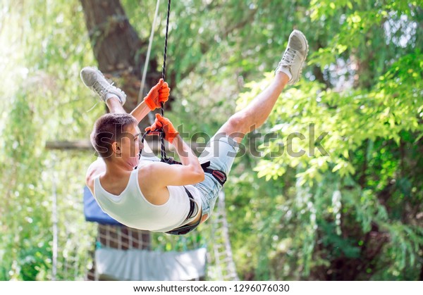 Man spend their leisure time in a ropes course. Man\
engaged in rope park.