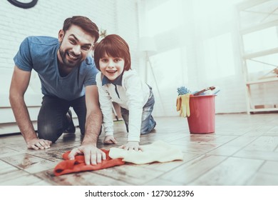 Man Spends Time With His Son. Father Is Engaged In Raising Child. Father Is Teaching A Son A Cleaning. Father And Son Washing The Floor With Rags. Persons Is Smiling. People Is Located In Bedroom.