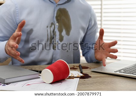 Man with spilled coffee over his workplace and shirt, closeup
