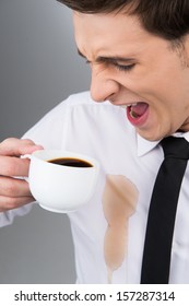 Man is spilling coffee on white shirt while drinking 