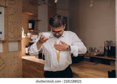 Man is spilling coffee on white shirt while drinking in office.
 - Powered by Shutterstock