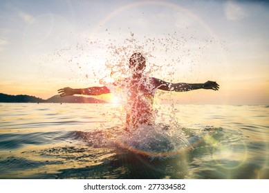 Man splashing water during summer holidays - Young attractive man having fun on a tropical beach at sunset