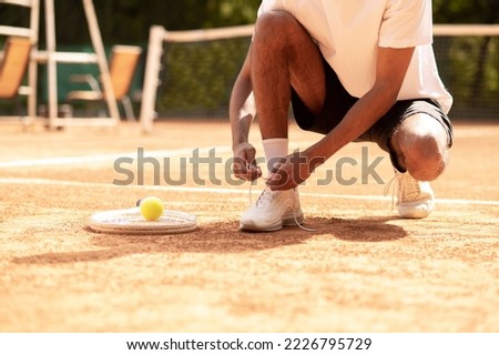Man in sports shorts tying shoe-strings on his sneakers