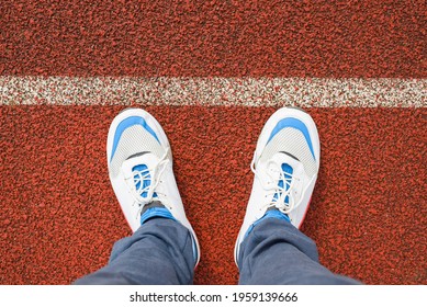 Man In Sports White Running Shoes Stands On The Red Jogging Track In The Stadium Outside, Close-up. Top View, First Person View