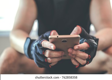 Man In Sportswear Sitting Use Mobile Phone In Gym