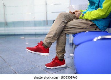 Man in sportswear is waiting on chair in hallway. Guy reads information from leaflet. Hiring for staff with no experience. Selection unskilled personnel. Advertising methods influencing people