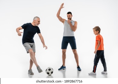 Man In Sportswear Whistling Near Granddad Playing Football With Grandson On White