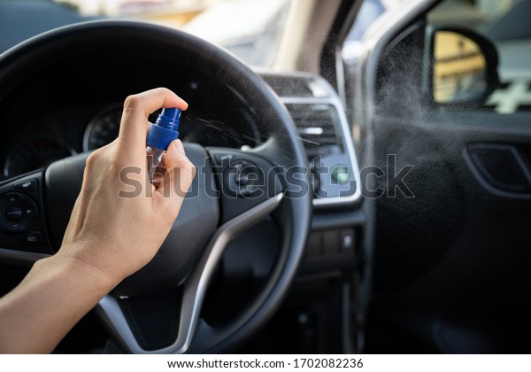 Man is\
spraying alcohol,disinfectant spray in car for prevention\
coronavirus disease (covid-19) contamination of germs and wipe\
clean surface, health care concept (select\
focus)
