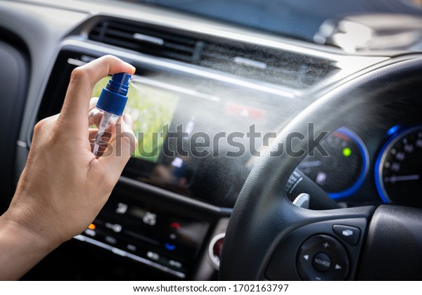 Man is\
spraying alcohol,disinfectant spray in car for prevention\
coronavirus disease (covid-19) contamination of germs and wipe\
clean surface, health care concept (select\
focus)