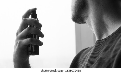 man spraying perfume. Handsome man with bottle of perfume on white background, closeup