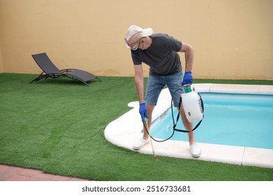 Man spraying pesticide on artificial grass near a swimming pool - Powered by Shutterstock