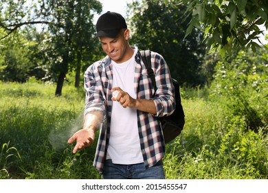 Man Spraying Tick Repellent On Arm During Hike In Nature