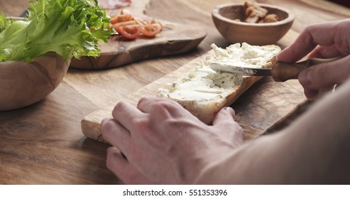 man spread cream cheese with herbs over baguette in slow motion, 4k photo