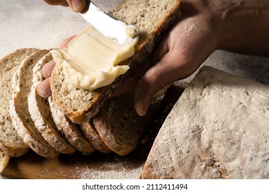 Man spreading cream cheese butter or a slice of bread slice on wood board. Dieting bread. Close-up. Healthy nutrition concept.  - Powered by Shutterstock