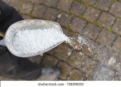 Ein Mann, der im Winter enteisendes Salz auf einem Weg verbreitet