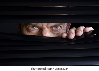 Man spying on something through venetian blinds