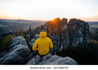 Man is squatting on the top of the mountain. Active recreation, climbing, trekking and hiking. Rocky towers. Beautiful moment the miracle of nature, during sunset or sunrise  - Powered by Shutterstock