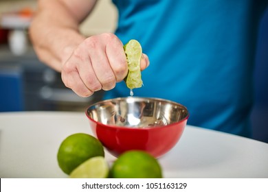 Man squeezing half a lime into a bowl, selective focus
