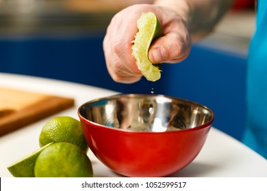 Man squeezing half a lime into a bowl, selective focus