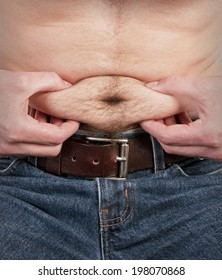 A Man Squeezing His Belly Fat Around His Belly Button.