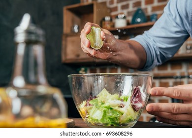 man squeezing lime into salad