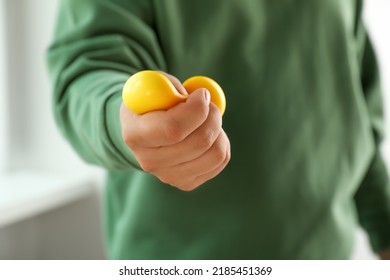 Man squeezing yellow stress ball indoors, closeup - Shutterstock ID 2185451369